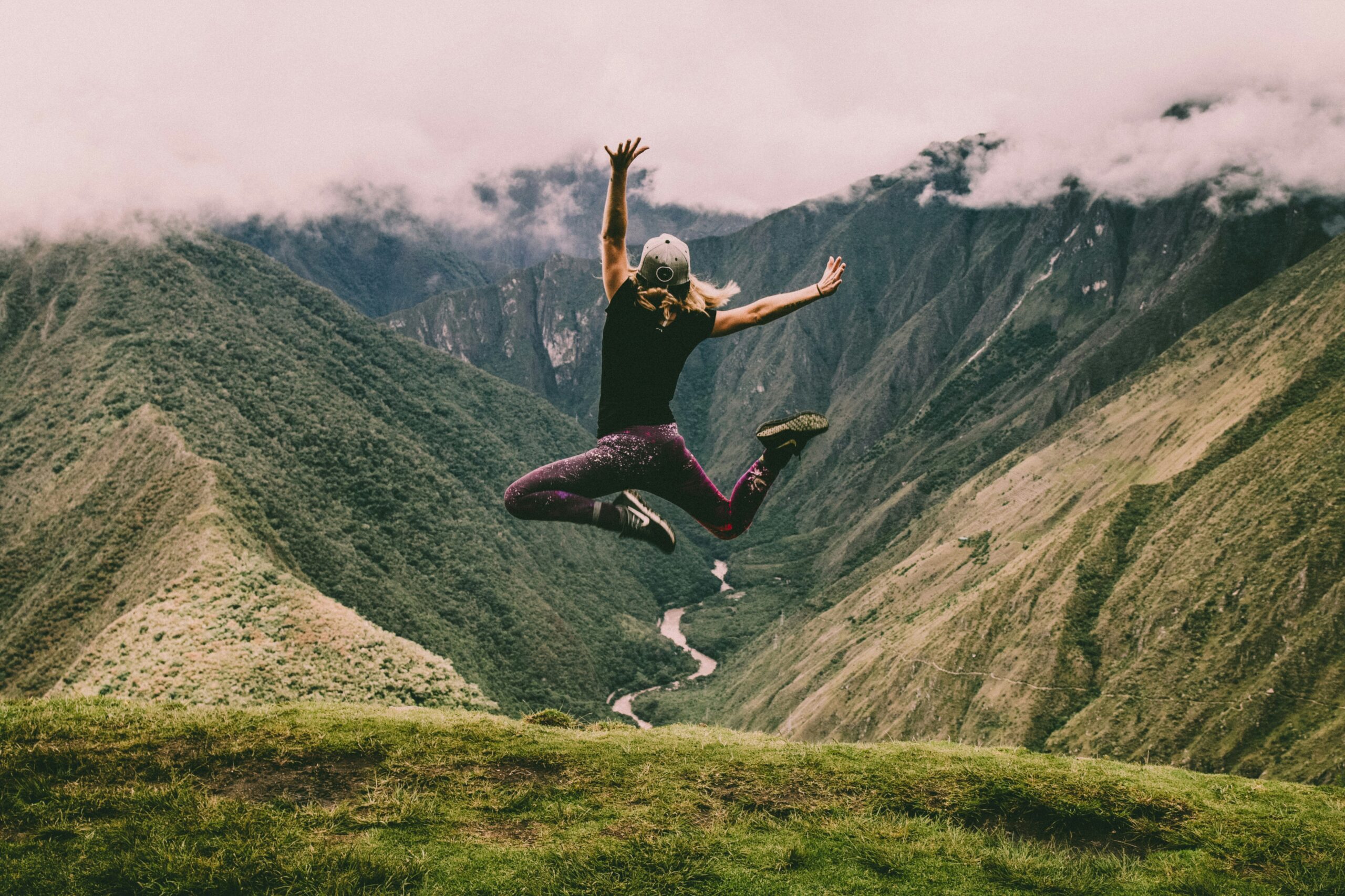 Image of woman jumping mid air in the mountains,