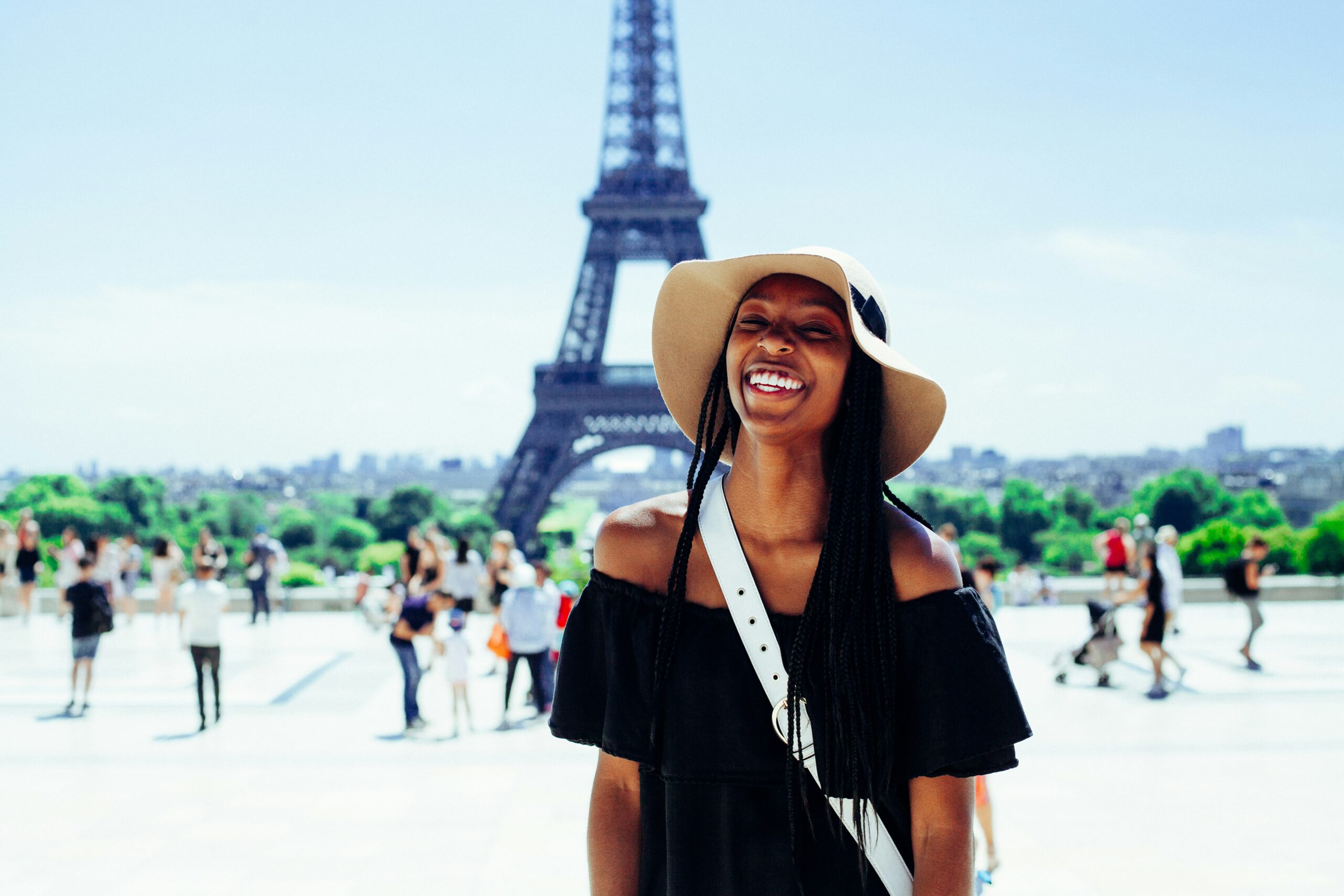 Young woman standing in front of the eiffel tower smiling.